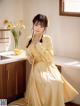 A woman in a yellow dress standing in a kitchen.