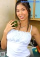 A woman holding a green bell pepper in a kitchen.