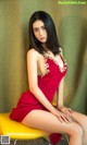 A woman in a red dress sitting on a yellow chair.