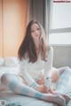 A woman sitting on a bed holding a can of soda.