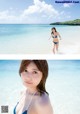 A woman in a blue bikini standing in the ocean.