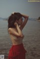 A woman in a red skirt standing on a beach.