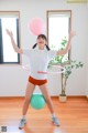 A woman is playing with a hula hoop and a ball.