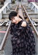 A woman in a black dress standing on a train track.