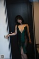 A woman in a green dress standing in front of a door.