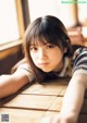 A young woman laying on a wooden table.