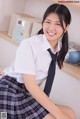 A young woman in a school uniform sitting on a bed.