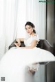 A woman in a wedding dress sitting on a chair.