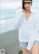 A woman standing on a beach next to the ocean.