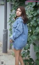 a woman in a denim jacket and shorts posing for a picture