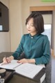 A woman sitting at a table writing in a notebook.