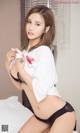 A woman in a white shirt and black panties on a bed.