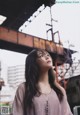 A woman standing in front of a bridge looking up.