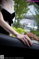 A woman in a black dress is looking out the window of a car.