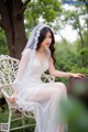 A woman in a wedding dress sitting on a white chair.