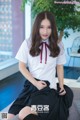 A woman in a white shirt and black skirt sitting on a couch.